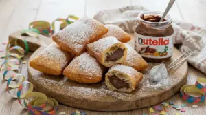 Bugie di Carnevale ripiene di Nutella, spolverate di zucchero a velo su tagliere di legno
